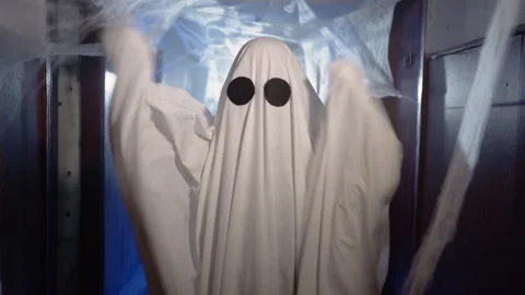 Halloween ghost in white sheet with black eyes arms up making boo gesture. Happy Stock Footage 314111386