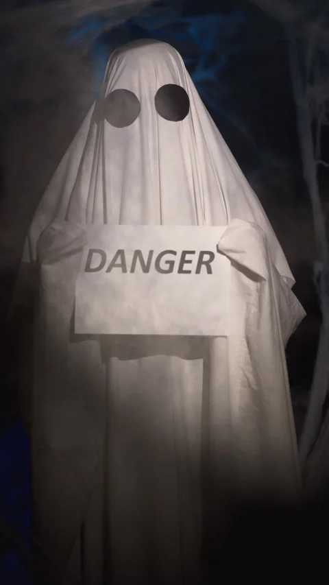 Halloween ghost in white sheet in dark corridor with spider web holding paper Stock Footage 314183147