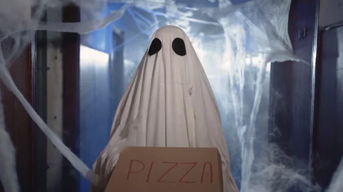 Halloween ghost in white sheet holding paper box with pizza. Happy halloween and Stock Footage 314305608