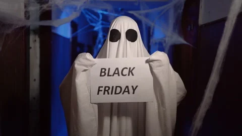 Halloween ghost in white sheet showing paper with Black Friday text. Happy Stock Footage 313556359