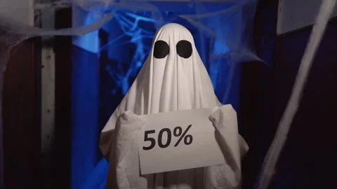 Halloween ghost in white sheet shows paper with 50 sale written text. Happy Stock Footage 313556528