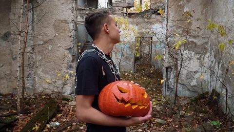 On Halloween guy in the form of a vampire with a pumpkin on his hands posing for Stock Footage 97054808