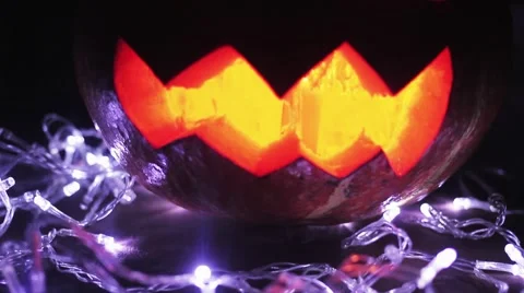 Halloween Jack o lantern with burning candle inside lay upon a white lights Video stock 68176582