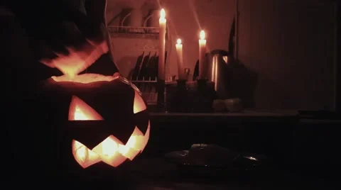 Halloween Jack o lantern with burning candle floats in dark kitchen floating Stock Footage 68310946