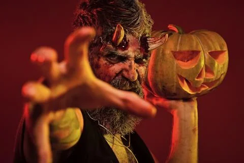 Halloween man devil hold pumpkin on red background 스톡 사진