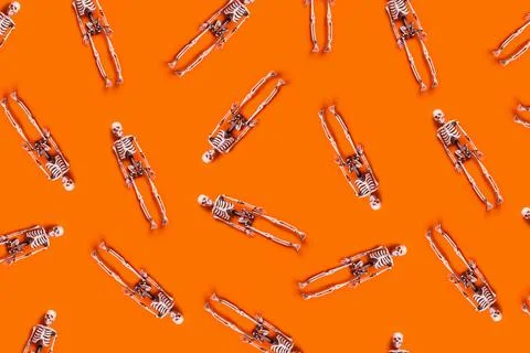 Halloween pattern of skeletons on orange background. Stock Photos