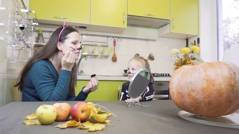 Halloween preparation. Mom does makeup to her little daughter. Sitting in the Stock Footage 113972631