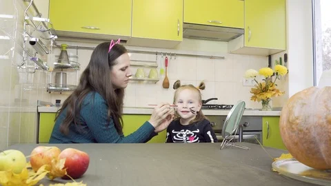 Halloween preparation. Mom does makeup to her little daughter. Sitting in the 库存影片 113974091