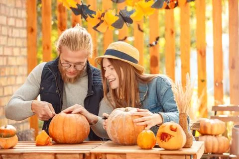 Halloween Preparaton Concept. Young couple sitting at table outdoors making jack Stock Photos