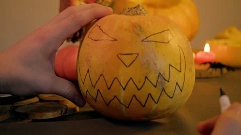 Halloween pumpkin being designed hand uses permanent marker to sketch out mouth Stock Footage 318938363
