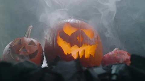 Halloween pumpkin on fire glowing inside in the dark. Scary Pumpkin with smoke a Video stock 252270430