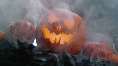 Halloween pumpkin on fire glowing inside in the dark. Scary Pumpkin with smoke a Stock Footage 252270475