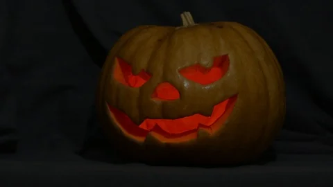 Halloween pumpkin head with cut out eyes and mouth, light inside flickering Stock Footage 112780843
