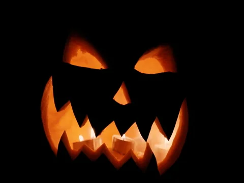 Halloween pumpkin head jack lantern with burning candles over black background Stock Footage 80137667