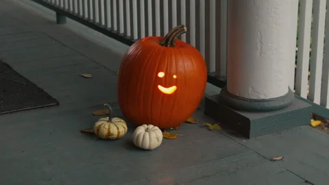 Halloween Pumpkin Jack-O'-Lantern Sits with Two Smaller Pumpkins Slow Motion 4K Video stock 308197081
