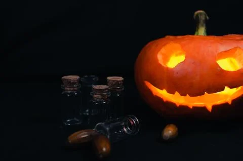 Halloween pumpkin next to empty magic cones on black background Stock Photos