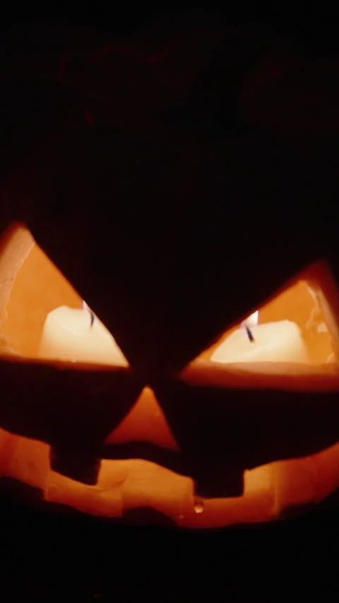 A Halloween pumpkin with two candles burning inside, with water dripping from it Stock Footage 247689232