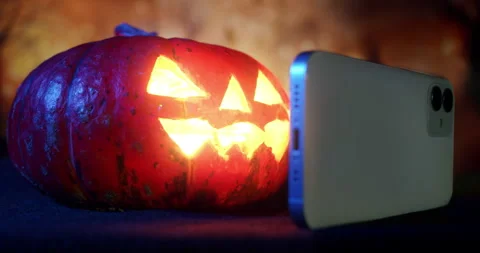 Halloween Pumpkin using smartphone, watching smartphone online Stock Footage 250366200
