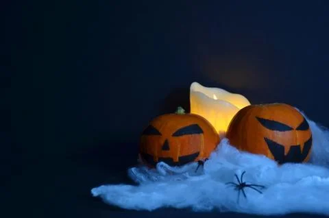Halloween pumpkin on the web. Candle on a black background. Stock Photos