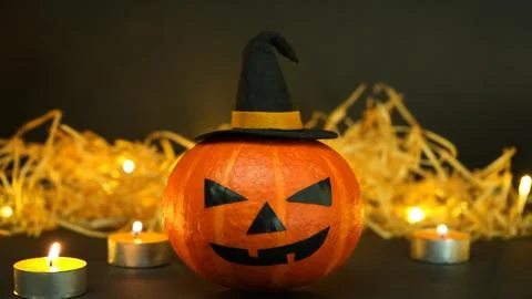 Halloween pumpkin with witch hat surrounded by flickering candles Stock Photos