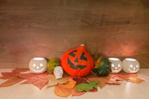 Halloween pumpkins, burning squash shape lanterns, skull-shaped toy, and dry  Stock Photos