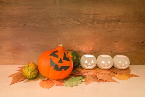 Halloween pumpkins, burning squash shape lanterns, and dry autumn leaves on w Stock Photos