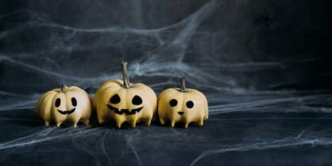 Halloween pumpkins in ghosts shape on dark gray background with spiderwebs Stock Photos