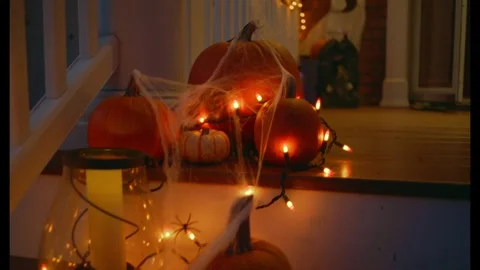 Halloween Pumpkins Illuminated by String Lights on a Wooden Front Porch at Night 库存影片 331110423