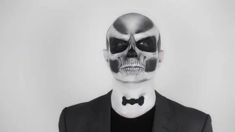 Halloween skeleton man in business suit turns and straightens drawn bow tie Vídeo Stock 139289853