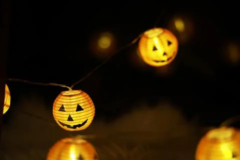 Halloween String Lights with Jack-O'-Lantern Faces Glowing in Dark Ambience Stock Photos