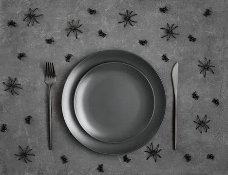 Halloween table setting. Empty black plate and cutlery, spiders on a dark  Stock Photos