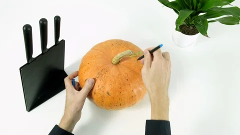 Halloween theme jack lantern. Guy draws scary face on pumpkin Stock Footage 102784151