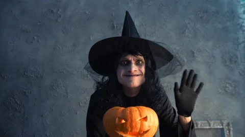 Halloween witch holding a pumpkin and waving his hand Stock Footage