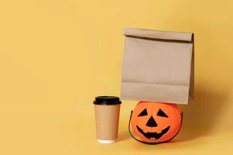 Halloween.Eco friendly paper coffee cup and pumpkin isolated yellow backgroun Stock Photos