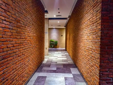 Hallway interior featuring textured brick walls and a tiled floor, leading .. Stock Photos