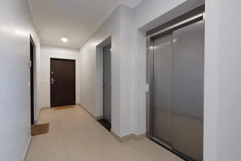 Hallway of a modern residential building with an elevator and apartment doors Stock Photos