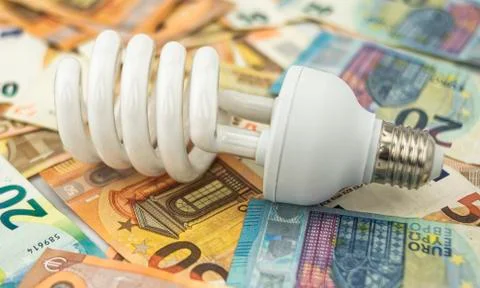 Halogen bulb lying on bed of twenty and fifty euro bills Stock Photos