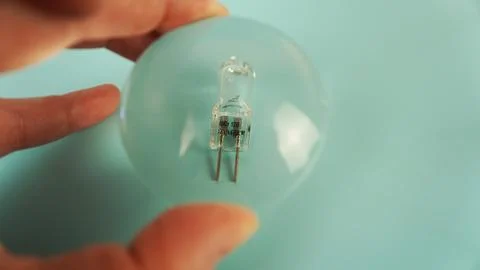 Halogen capsule lamp G4 through a magnifying glass. Stock Photos