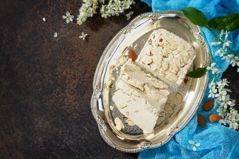 Halva with almond petals on the kitchen table. Turkish and Arabic sweets. Stock Photos