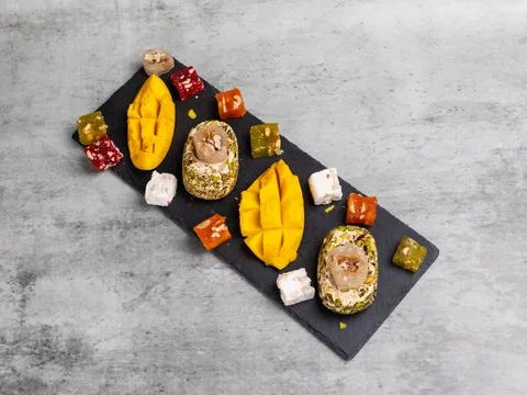 Halva, fresh mango and fruit sweets with nuts on the cutting board. Stock Photos