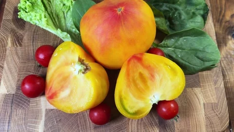 Halved and whole heart shaped orange pink tomato, cherry tomatoes Stock Footage 346473170