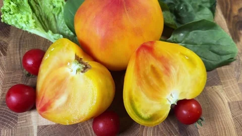 Halved and whole heart shaped orange pink tomato, cherry tomatoes Stock Footage 346473175