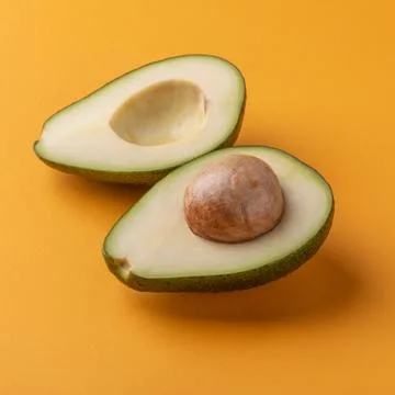 Halved avocado with kernel on orange background Stock Photos