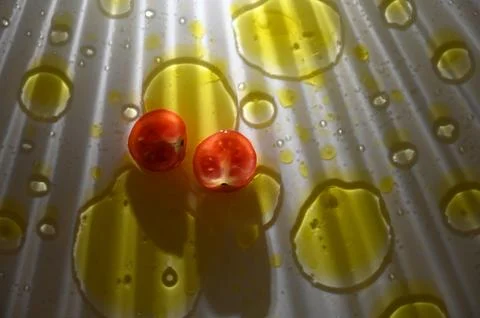 Halved cherry tomatoes on a white ribbed surface with olive oil drops Stock Photos