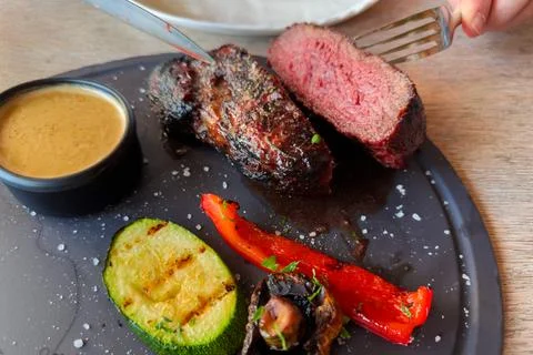 Halved Medium Rare beef steak with grilled vegetables on dish Stock Photos