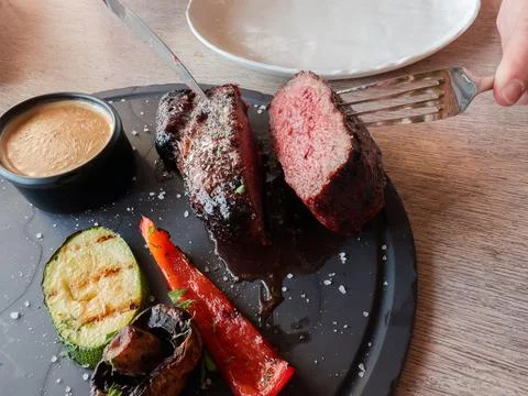 Halved Medium Rare beef steak with grilled vegetables on dish Stock Photos
