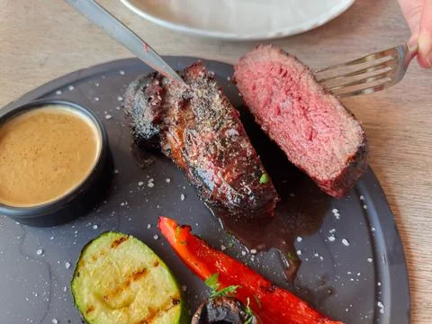 Halved Medium Rare beef steak with grilled vegetables on dish Stock Photos