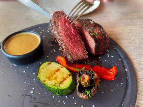 Halved Medium Rare beef steak with grilled vegetables on dish Stock Photos