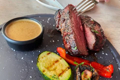 Halved Medium Rare beef steak with grilled vegetables on dish Stock Photos