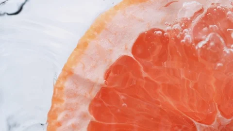 Halved pink grapefruit falling in water. Slow Motion. Video stock 87239570